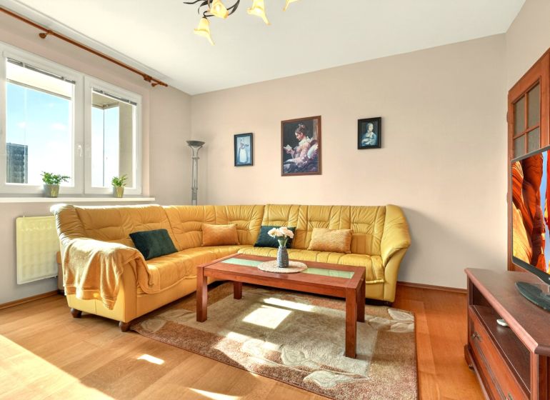 Living room in a 3-room apartment with a corner sofa and a wooden decor floor.