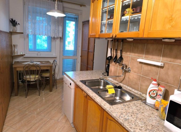 A kitchen in a 3-room apartment with a wooden decor floor and a dining table.