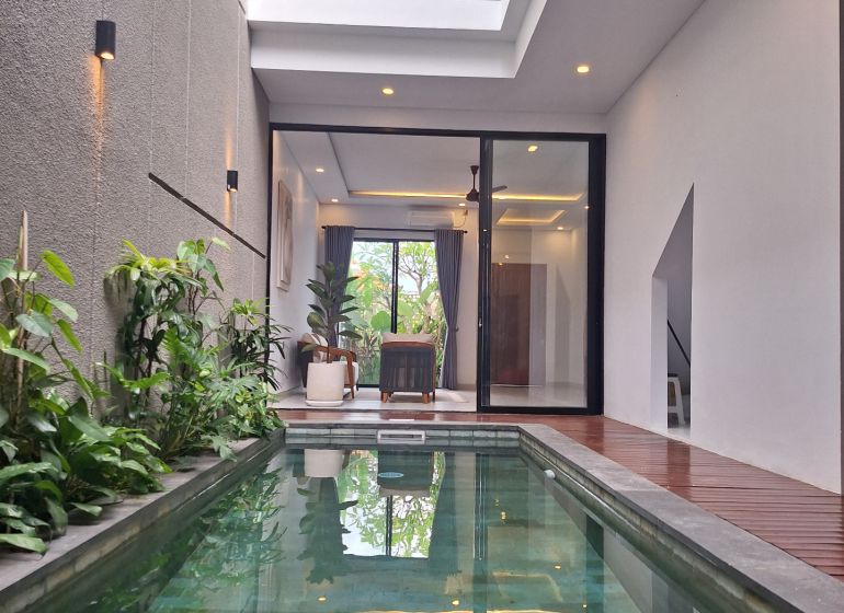 Villa in Bali with a pool and plants, terrace with wooden decor flooring.