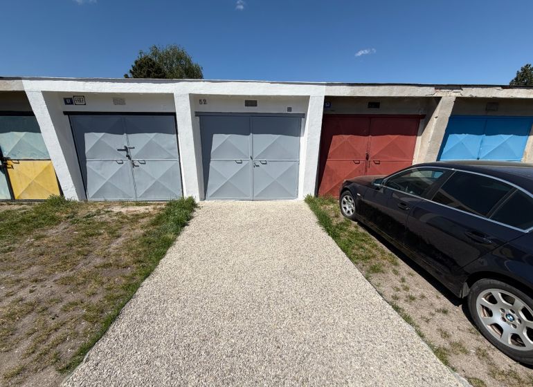 Garages on Bezručova Street in Trenčín with a car parked next to them on the grass.