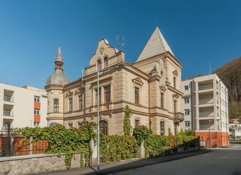 A historical building in Trenčianske Teplice next to modern apartment buildings.