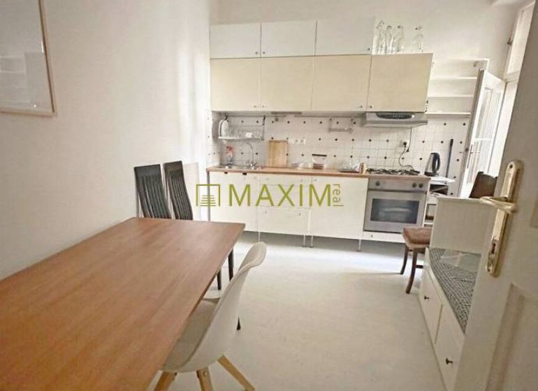 A kitchen in a 3-room apartment with a dining table and white furniture.