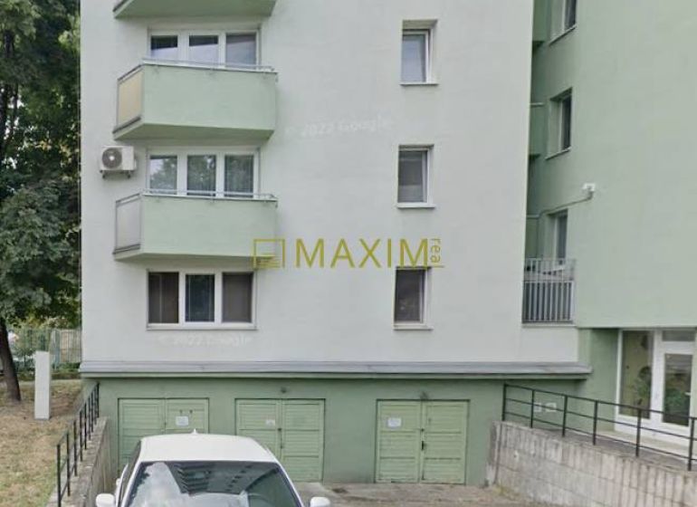 Building and garages in Bratislava - Ružinov on Ružová dolina, white car parked in the foreground.