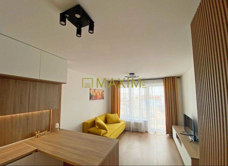 Living room with wood-patterned flooring, a yellow sofa, and modern lighting in a two-room apartment.