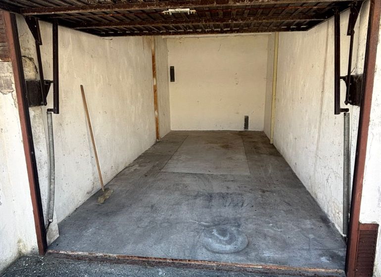 An open garage on Dopravná Street in Piešťany with a concrete floor and a broom.