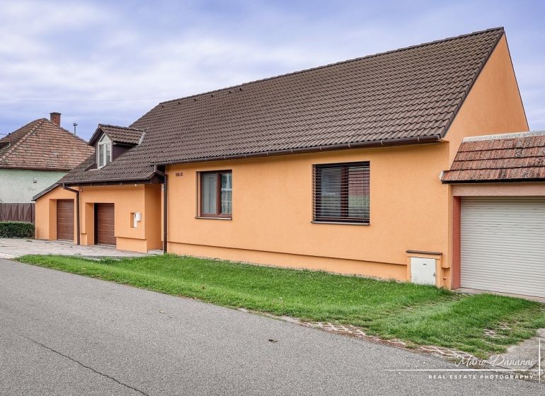 A family house on a street in Špačince with a gable roof and an orange facade.