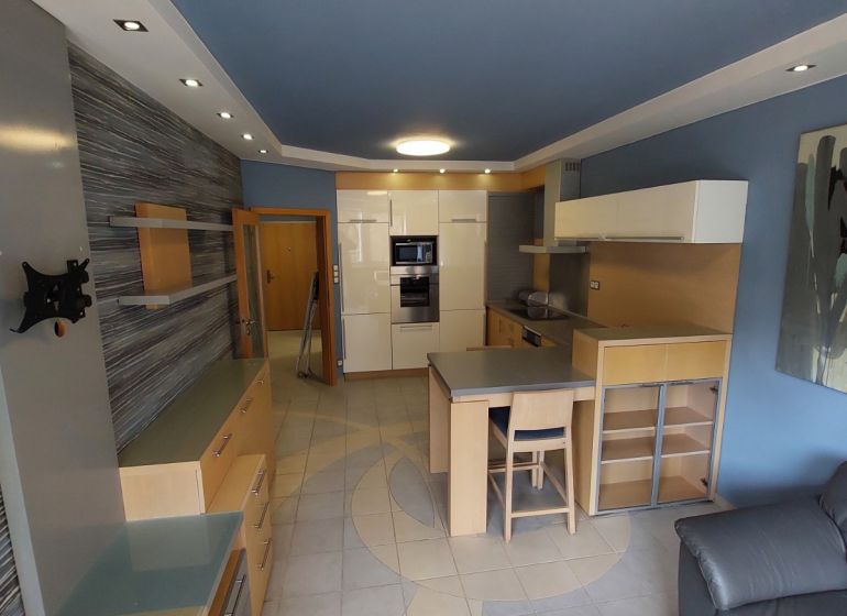 A kitchen in a 2-room apartment with light furniture and a blue ceiling.
