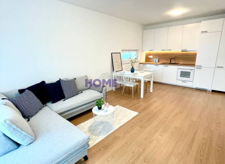 A stylish living area in a 3-room apartment with a wooden decor floor and a kitchenette.