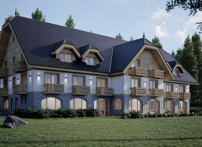 A hotel in the High Tatras with wooden balconies and a stone facade surrounded by greenery.