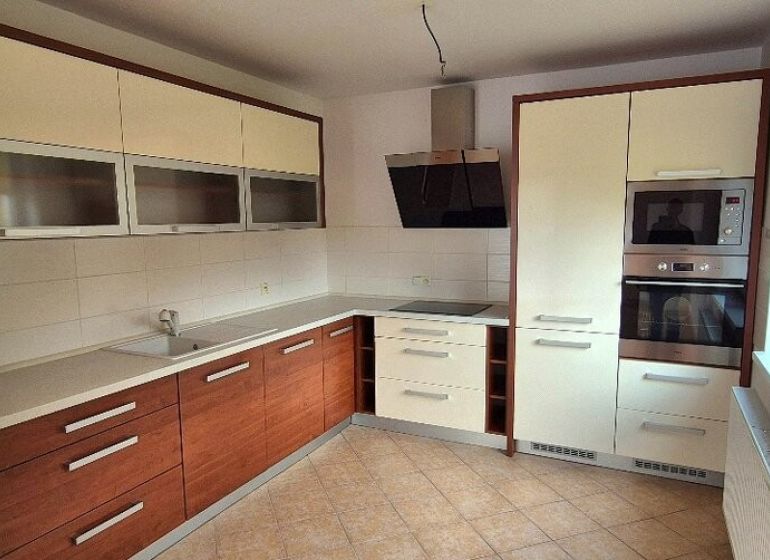 A kitchen with a corner unit in a family house, white cabinets, and ceramic flooring.