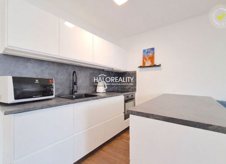 A kitchen in a 2-room apartment with a white kitchen unit and a floor with a wood decor.