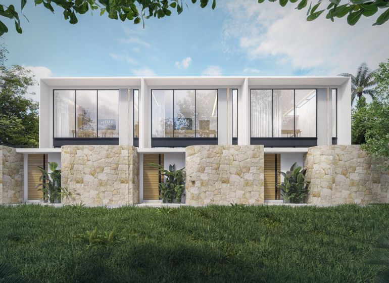The exterior of a villa in Bali with stone walls and large glass windows.