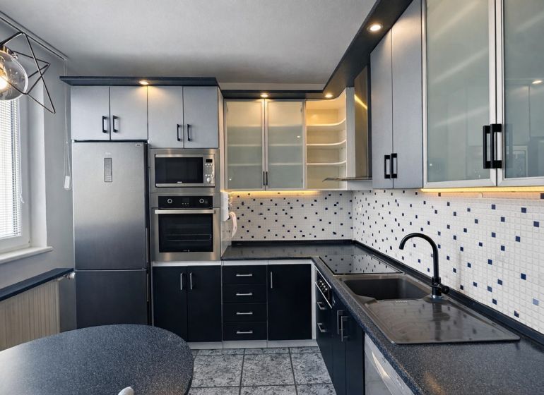 A kitchen in a 3-room apartment with ceramic tiles and spot lighting.