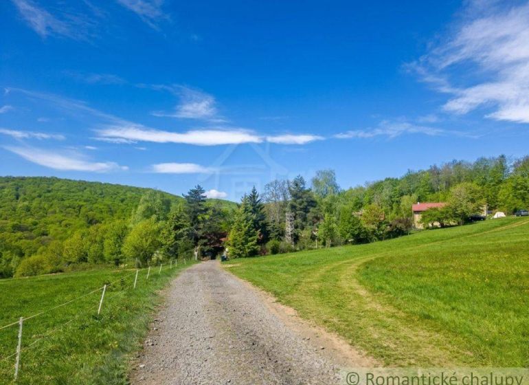 The path leads to a family house in Cinobana, surrounded by greenery and a blue sky.