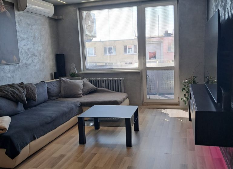 Living room with a sofa, black table, and wooden decor flooring.