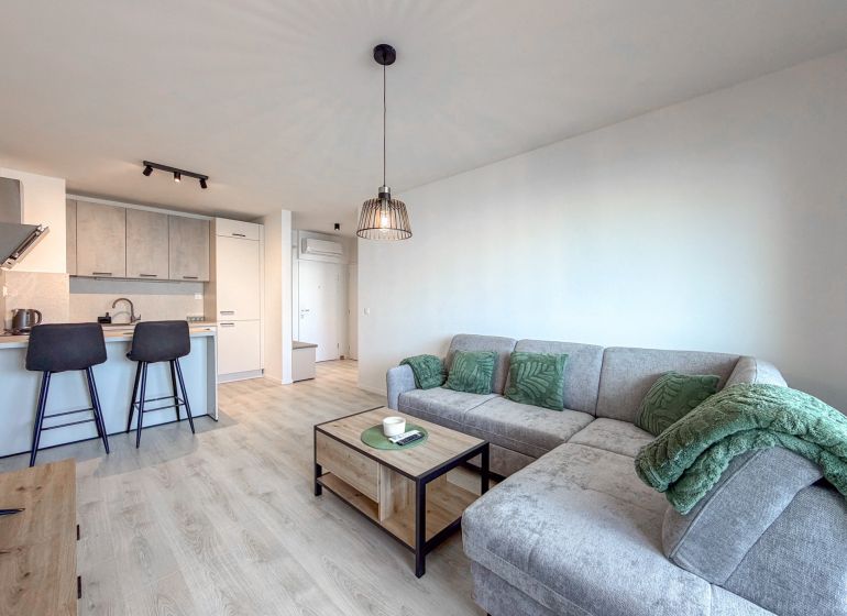 A bright living room with an open kitchen in a two-room apartment and a floor with a wooden decor.