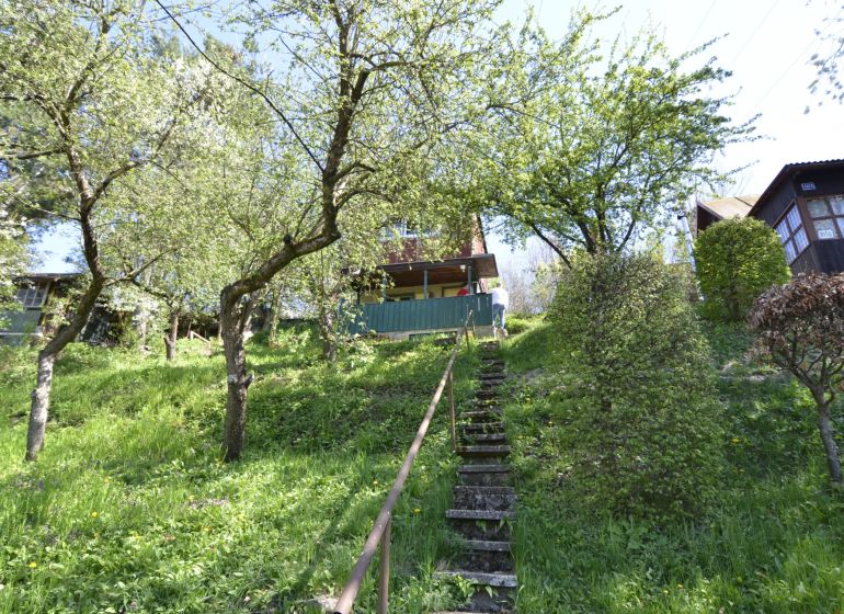 The staircase leads through a grassy garden in the city of Zvolen, surrounded by trees and shrubs.