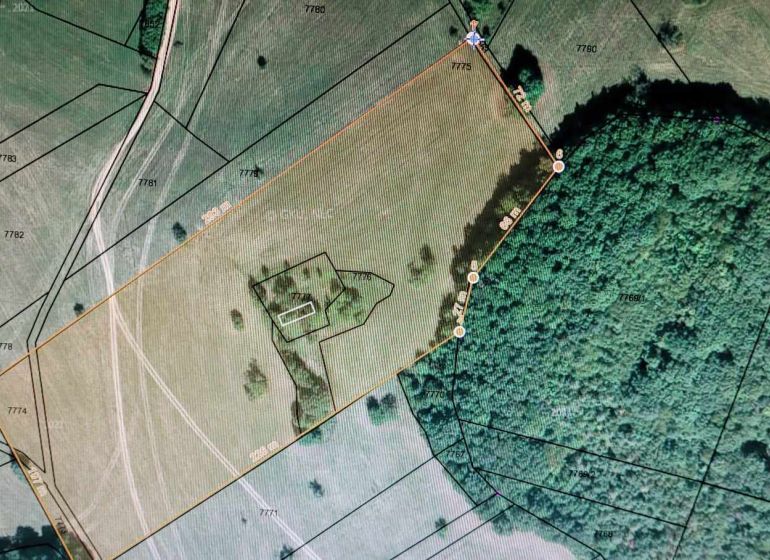 Aerial view of a plot surrounded by forest, ideal for living and investment.