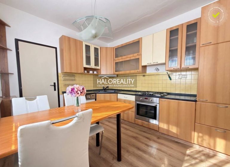 A kitchen in a 3-room apartment with a wood-patterned floor and a dining table.