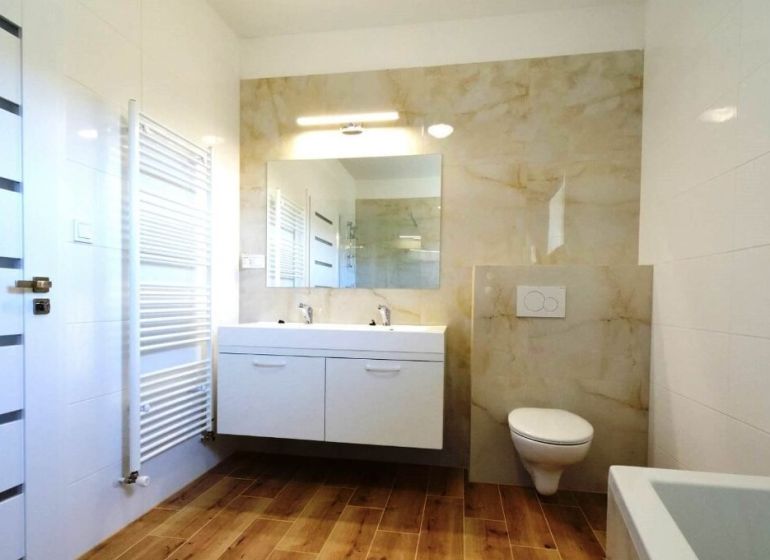 A bathroom in a family house with a wooden decor floor, double sink, and a shower.