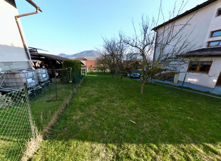 Gardens in Kysucké Nové Mesto with lawns, trees, houses, and a view of the mountains.