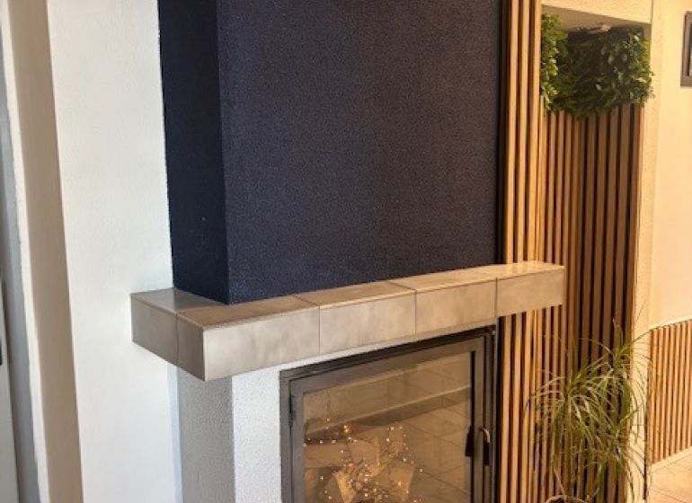 Office interior with a fireplace, flowers, and wooden wall paneling.