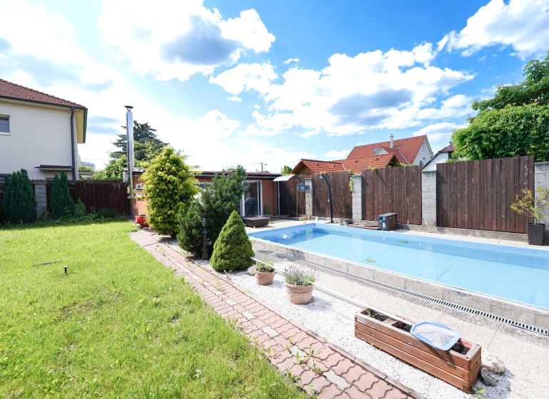 The family house on Kladnianska Street in Bratislava-Ružinov has a swimming pool, a lawn, and a fenced yard.