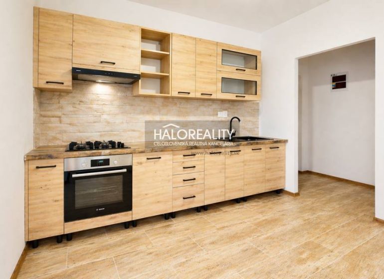 A kitchenette in a studio apartment with a wood-patterned floor and built-in appliances.