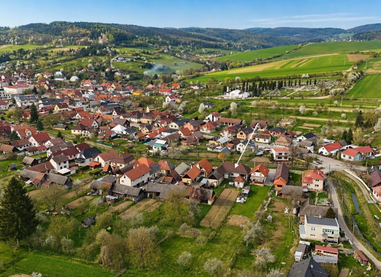 An aerial view of family houses in Horné Súčany surrounded by green fields and hills.