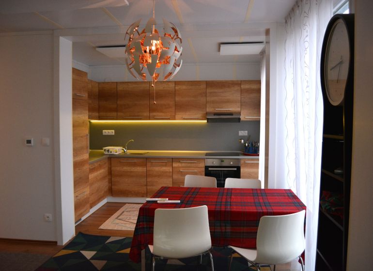 A kitchen with a wood-patterned floor, a table, and decorative lighting in a family house.