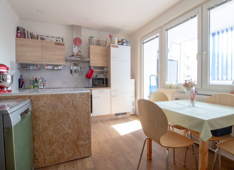 A kitchen in a 2-room apartment with a table and a wooden decor floor.