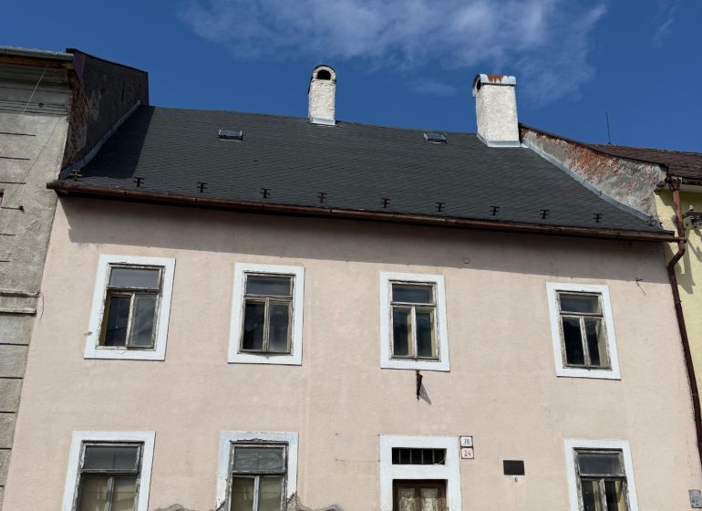 A family house in Kremnica with a worn facade and a stone plinth section.