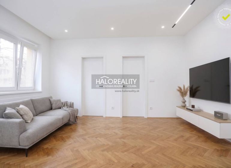 Living room in a 3-room apartment with a wood-patterned floor and a TV on the wall.