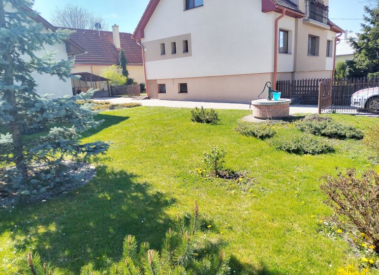 A family house in Martin with a lawn, a pine tree, and a well in the garden.