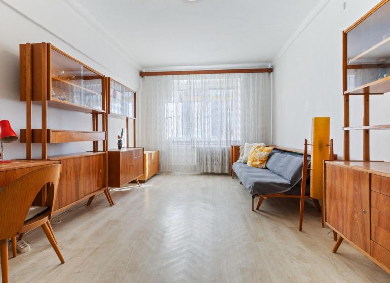 A living room in a 3-room apartment with a wooden decor floor and retro furniture.