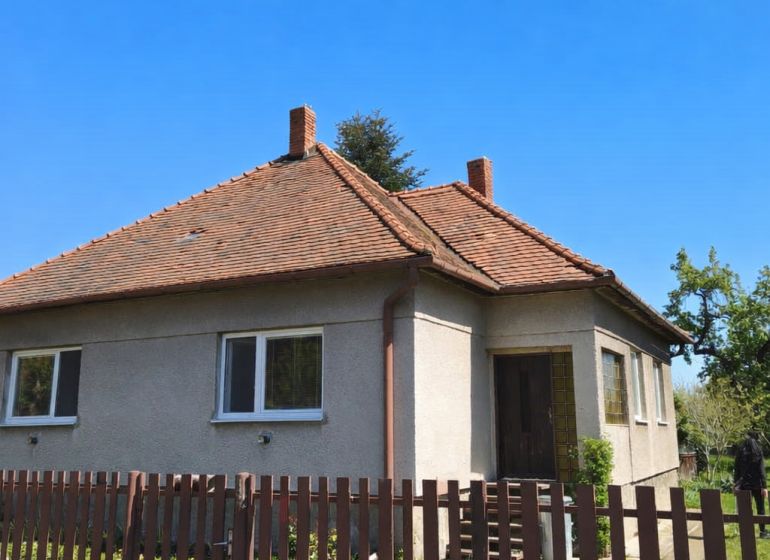 A family house in Zlaté Moravce with a sloped roof and a fence in the foreground.