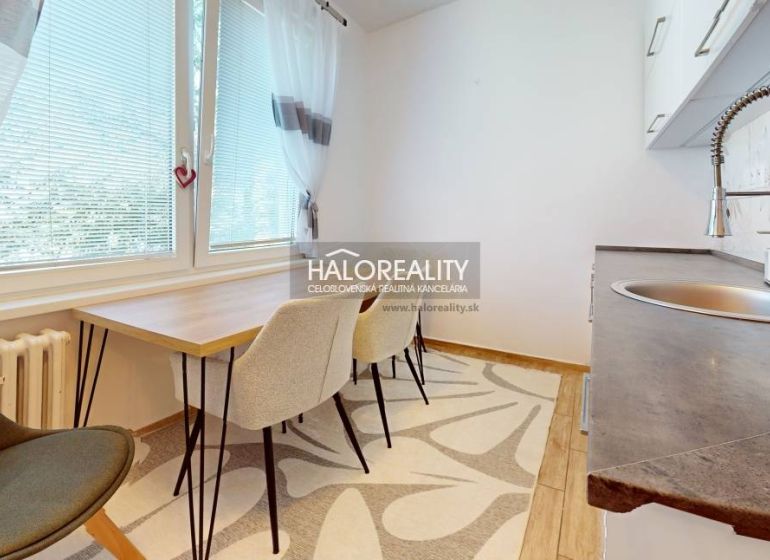 A kitchen in a 2-room apartment with a dining table and a floor with a wooden decor.