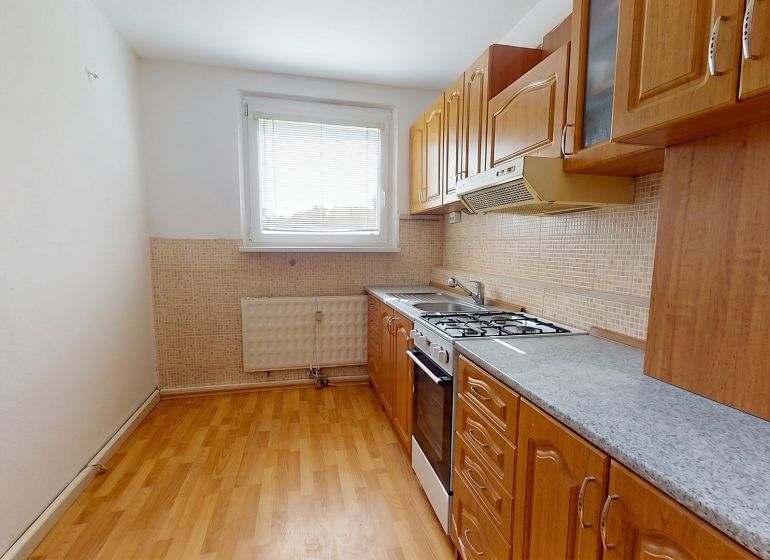 A kitchen in a 3-room apartment with a kitchen unit and a floor with a wooden decor.