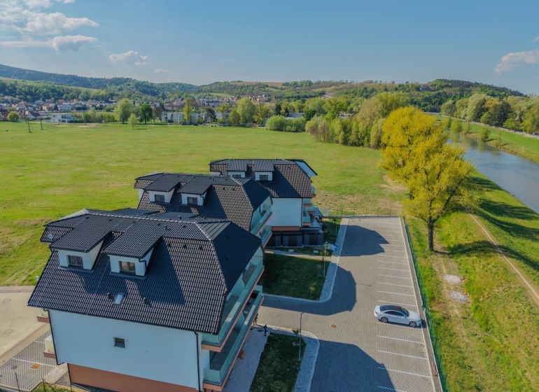 New buildings by the river on Moravanská Street in Banka with parking spaces.