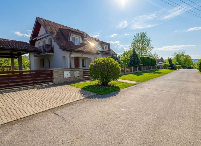 A family house in Sliač, a spacious street surrounded by green trees and a blue sky.