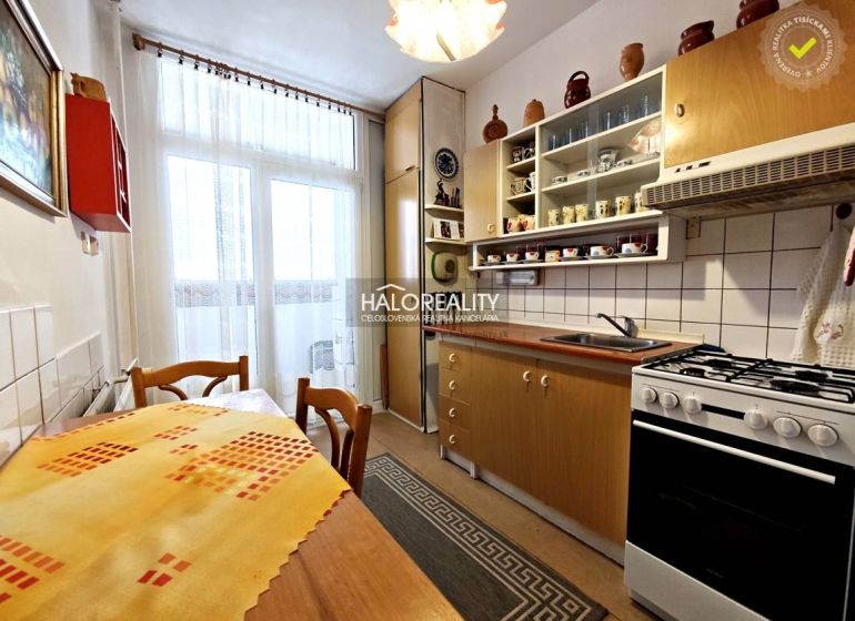 A kitchen in a 2-room apartment with a wooden decor floor and a balcony window.