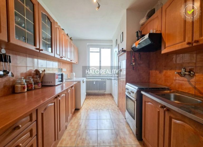 A kitchen in a 3-room apartment with wooden cabinets and a floor with a wood decor.