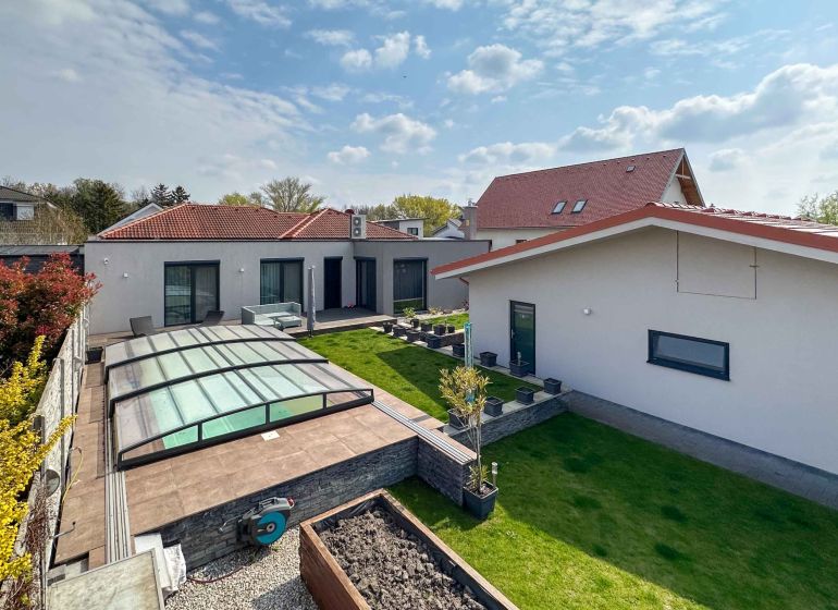 A family house in Pama with a landscaped garden, glass shelter, and lawn.