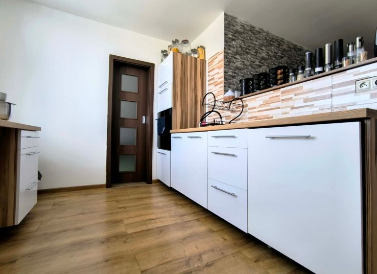A kitchen in a 3-room apartment with white cabinets and a wood-patterned floor.