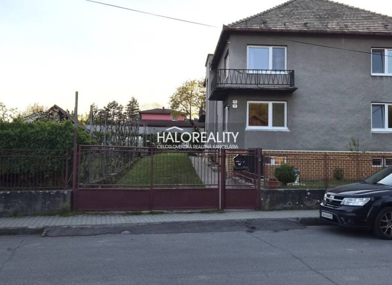A family house in Poltár with a front garden and a car parked on the street.