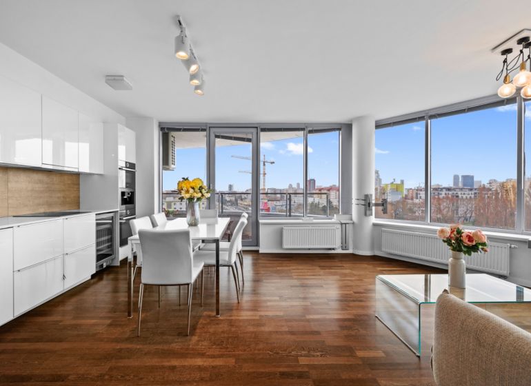 A kitchen in a 3-room apartment with white cabinets and a wood-patterned floor.