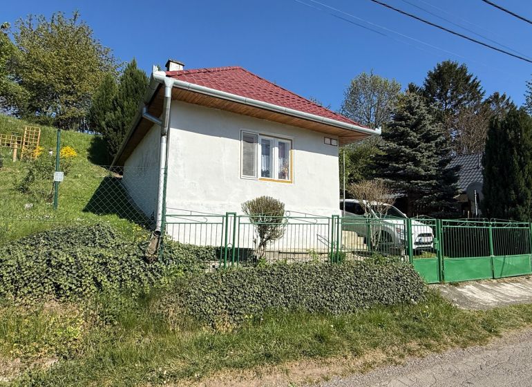 A family house in Čaradice with a red roof and green gates in the garden.
