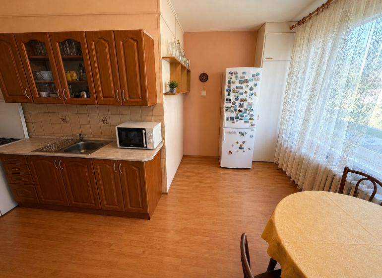 A kitchen in a 3-room apartment with a wood-patterned floor and a dining area.