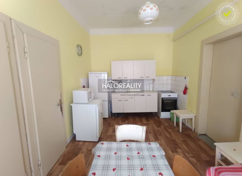 A kitchen in a 2-room apartment with a wooden decor floor and basic appliances.