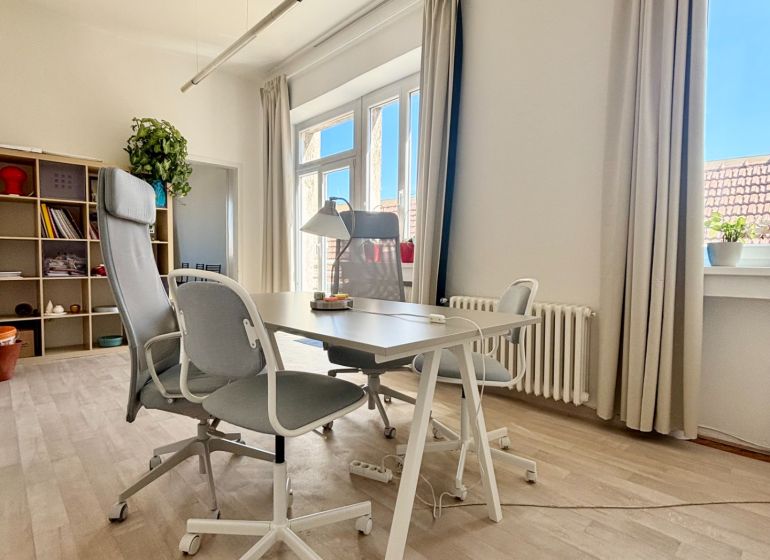 Offices with large windows, a desk and chairs, and a floor with a wooden decor.